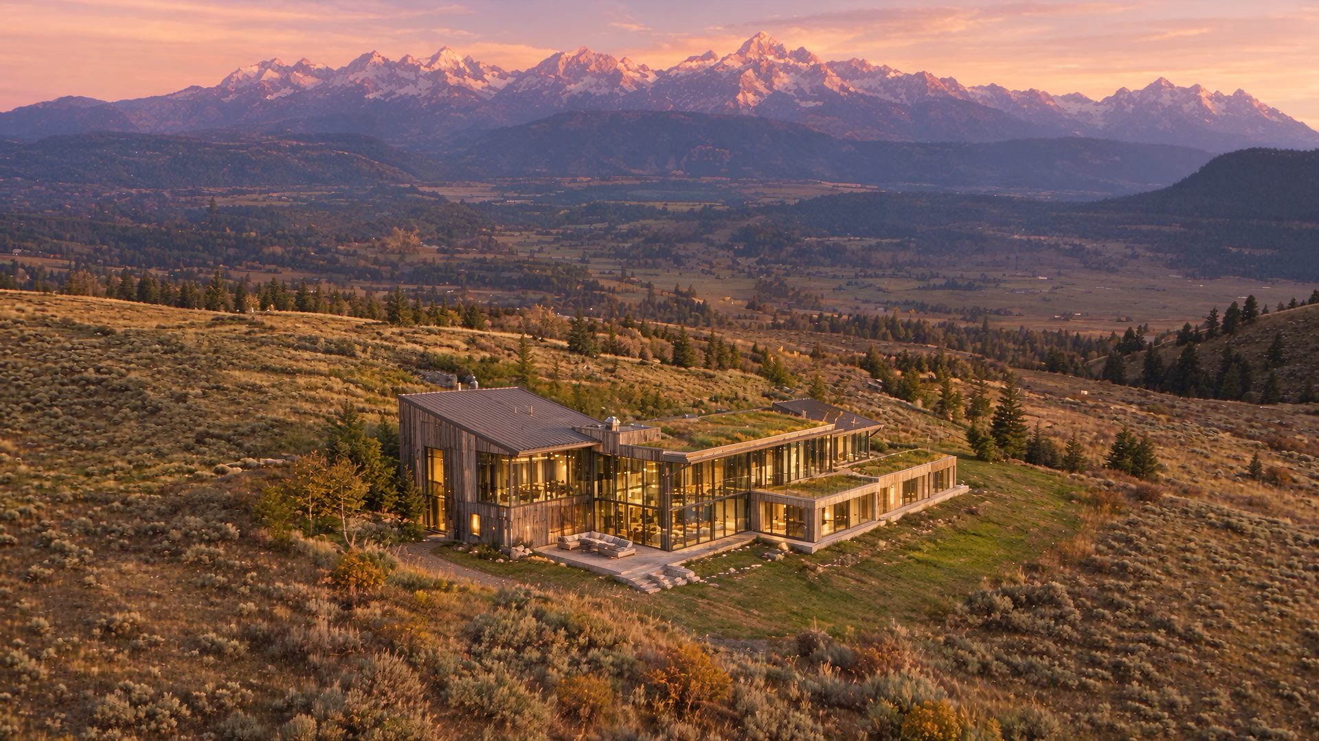 The glass and cedar manor on the ridge above Jackson at last light, the Teton range behind